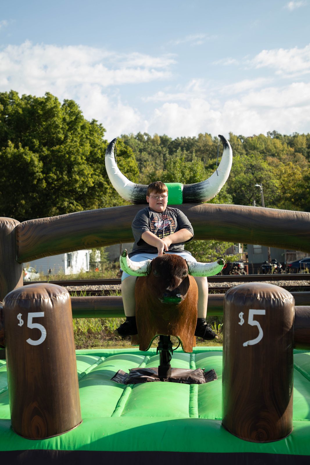 Boy riding the mechanical bull under a blue sky
