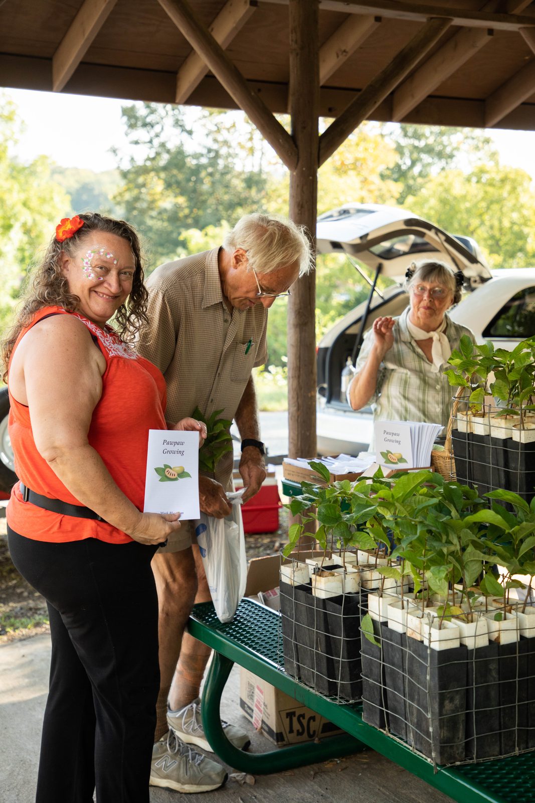Face-painted visitor smiling with a pawpaw growing booklet