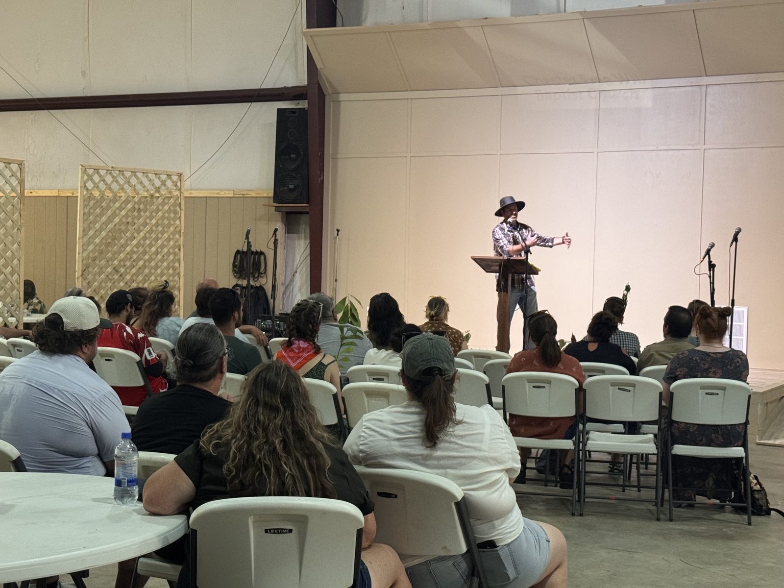Speaker at a podium addressing a fully seated audience at the Life Center